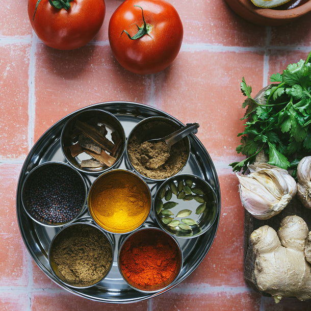 A photo f an Indian Spice Tin (Masala Dabba) filled with Indian Spices