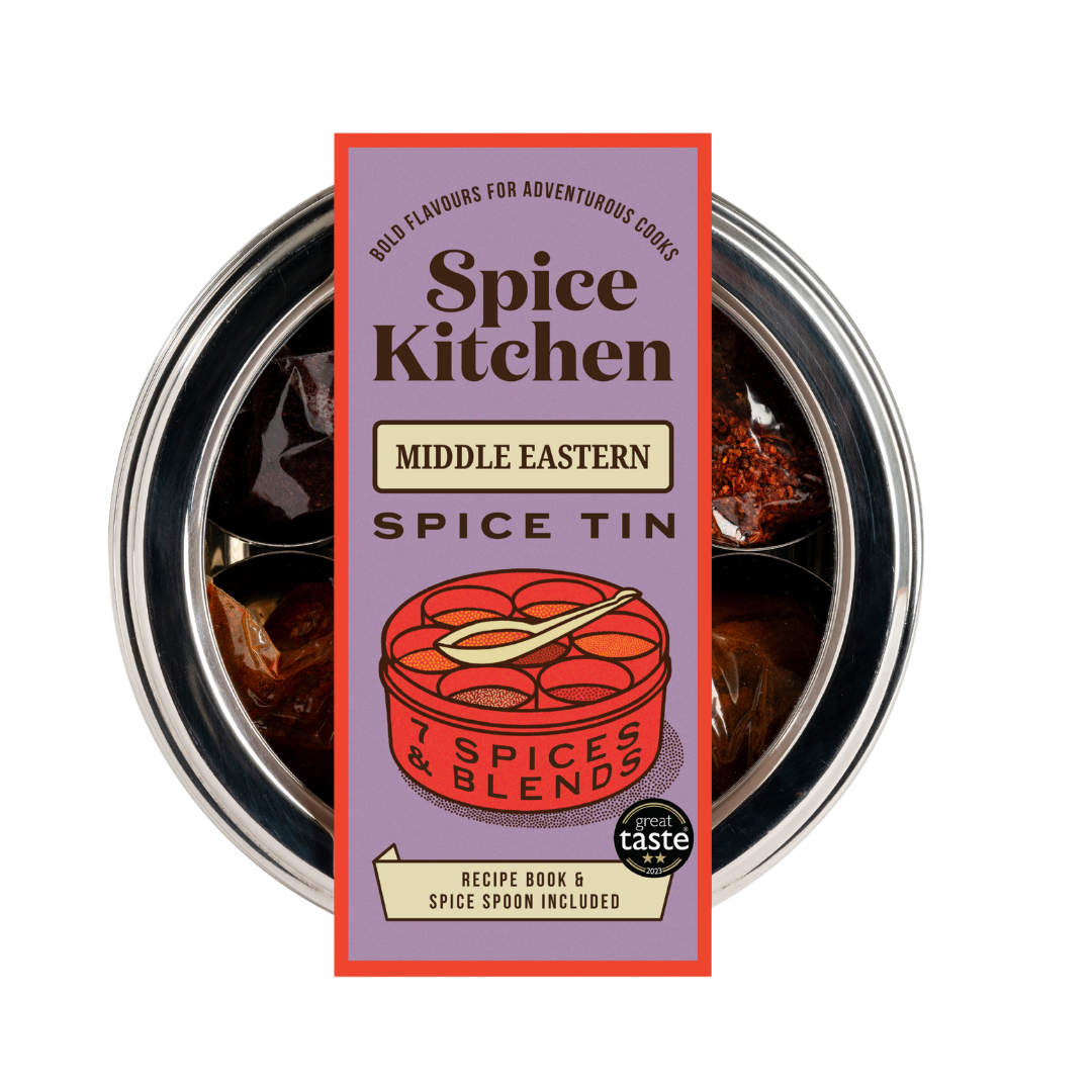 A Spice Kitchen Middle Eastern spice tin with a red and yellow floral patterned silk sari gift-wrap. The tin is labeled with various spice names and includes a mini recipe book and spice spoon.