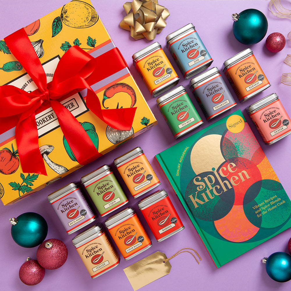 Spice Kitchen Signature Spice Blend & Cookery Book Gifting Hamper set with colourful tins and Sanjay Aggarwal's cookery book on a purple background