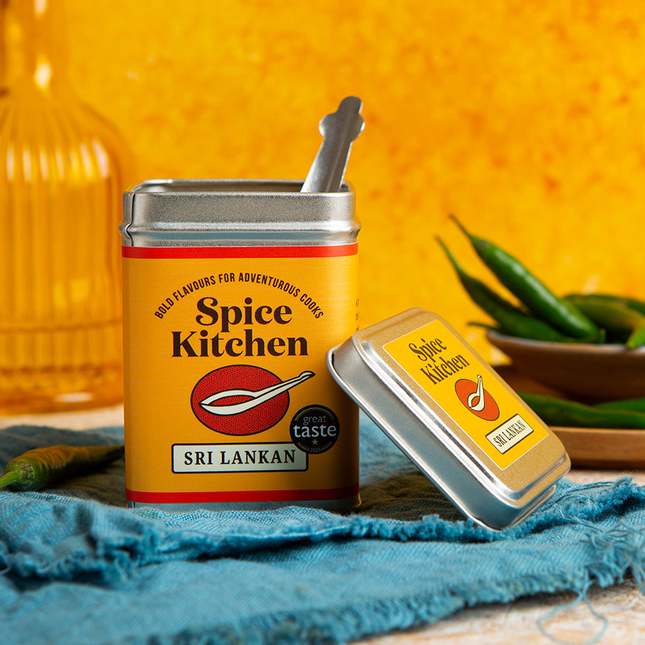 Spice Kitchen Sri Lankan spice tin with a spoon on a blue cloth against an orange background
