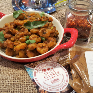 Dry prawn masala curry served in a tomato red ceramic pan with scattered fresh coriander