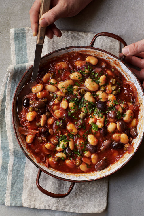 A Pot full of delicious Bean Puttanesca being served.