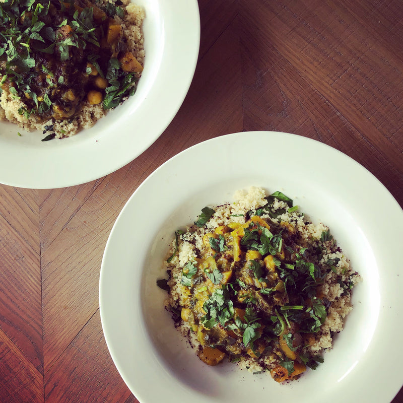 Vegetarian aubergine and squash tagine served on a bed of fluffy couscous, garnished with a handful of spinach and fresh coriander 
