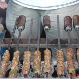 Skewers of grilled kebabs cooking over charcoal barbecue
