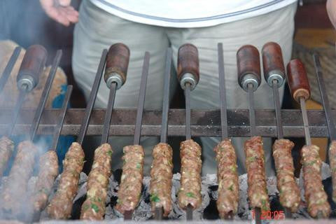 Skewers of grilled kebabs cooking over charcoal barbecue