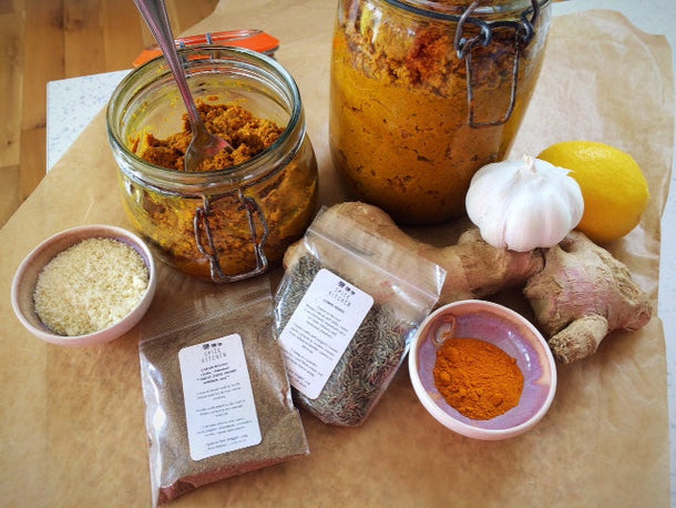 A jar of masala curry paste surrounded by ingedients including garlic, ginger, lemon and Spice Kitchen's garam masala blend