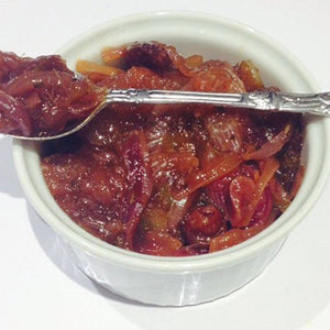 Homemade onion chutney served in a white ramekin with spoon