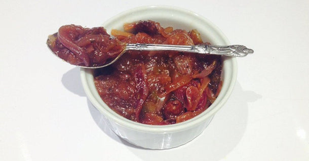 Homemade onion chutney served in a white ramekin with spoon