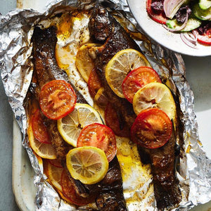Two freshly baked Trouts in foil served with a side salad.