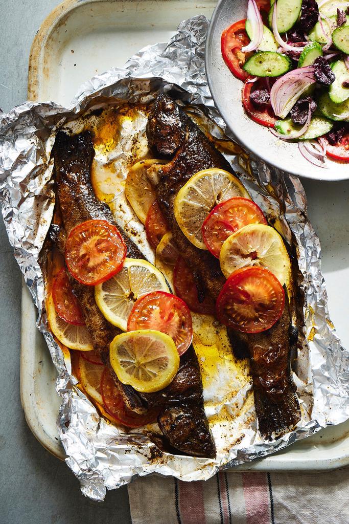 Two freshly baked Trouts in foil served with a side salad.
