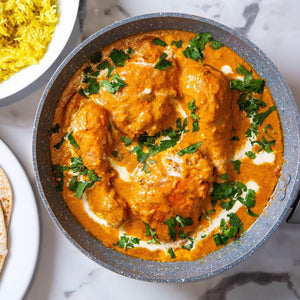 Rich Butter Chicken, garnished with fresh coriander and cream and served with pilau rice and parathas