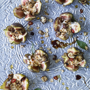 Decorative blue plate scattered invitingly with fleshy figs and hazelnut crumble, spiced yoghurt and a drizzle of balsamic syrup.