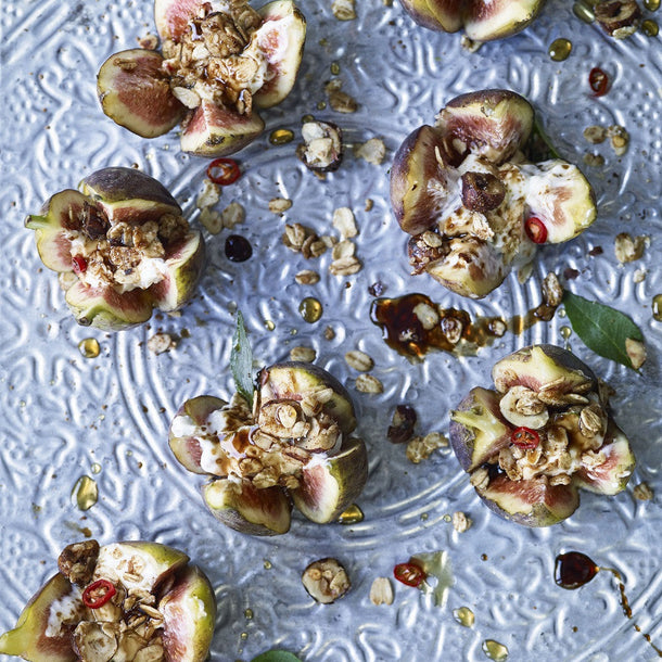 Decorative blue plate scattered invitingly with fleshy figs and hazelnut crumble, spiced yoghurt and a drizzle of balsamic syrup.