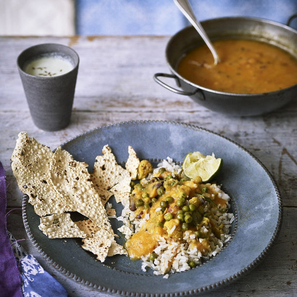 A thali of a warming Gujarati lentil dal served on a bed of white rice with a crispy poppadom on the side