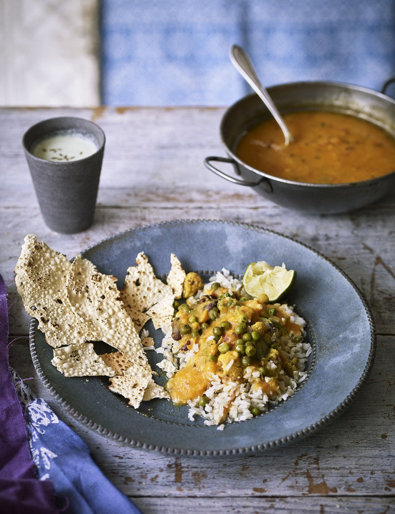 A thali of a warming Gujarati lentil dal served on a bed of white rice with a crispy poppadom on the side