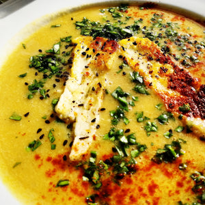 Harissa spiced lentil soup with golden grilled slices of halloumi cheese garnished with fresh parsley and Nigella seeds.
