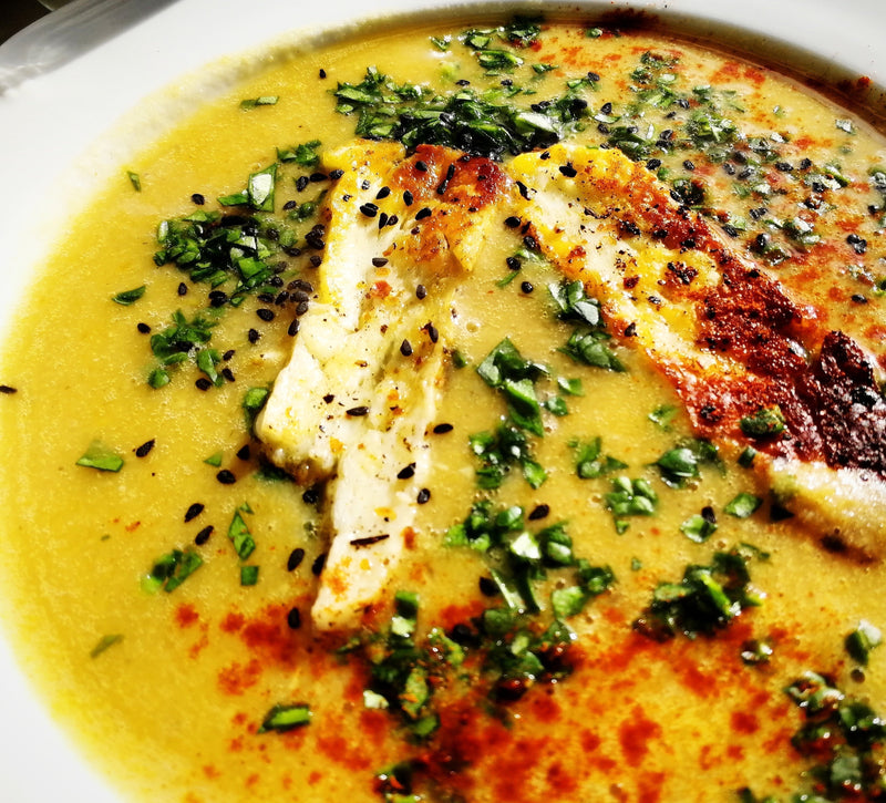 Harissa spiced lentil soup with golden grilled slices of halloumi cheese garnished with fresh parsley and Nigella seeds.
