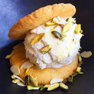 Fluffy Shrikhand Ice Cream sprinkled with pistachios in between flaky, buttery puri