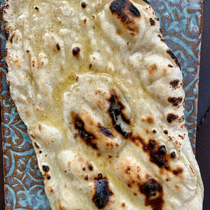 Soft flat bread, lightly cooked and golden, served warm with a tender, pliable texture.