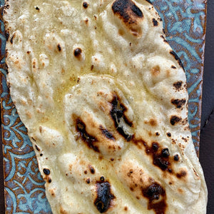 Soft flat bread, lightly cooked and golden, served warm with a tender, pliable texture.