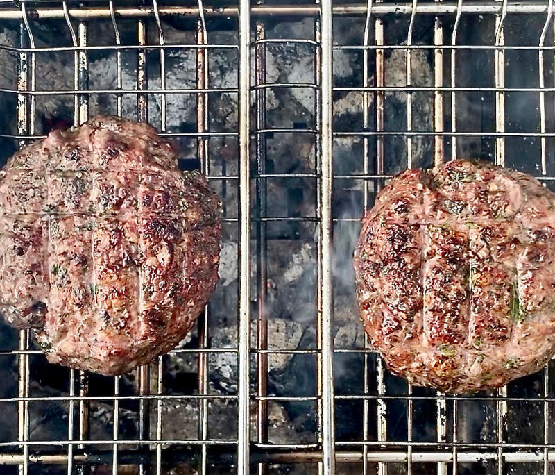 Juicy za'atar lamb burgers being grilled side by side over hot barbeque coals