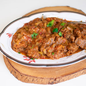 A juicy moroccan beef stew served in a decorative casserole dish, garnished with chopped parsley