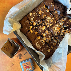 A freshly baked Chai Brownie still in the baking tray, with a Spice Kitchen Chai-spiced Spice blend placed next to it. 