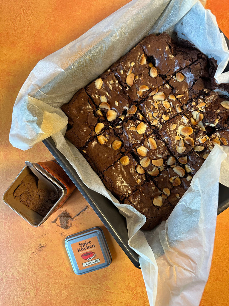 A freshly baked Chai Brownie still in the baking tray, with a Spice Kitchen Chai-spiced Spice blend placed next to it. 