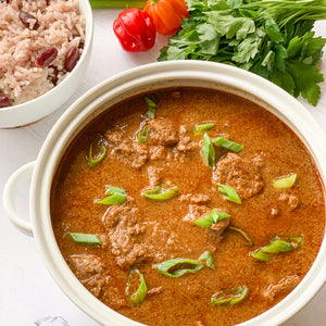 A pot of Jamacian beef stew next to a bowl of delicious rice and peas.