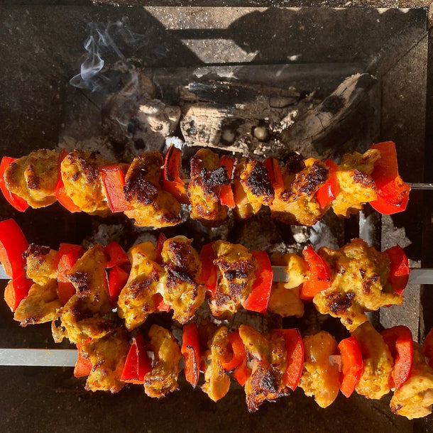 Spicy chicken and red pepper kebabs set on skewers over hot barbecue coals.