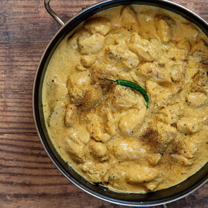 Mithi Ahmed mild and creamy Chicken Korma in a steel serving dish with a single green chilli on top