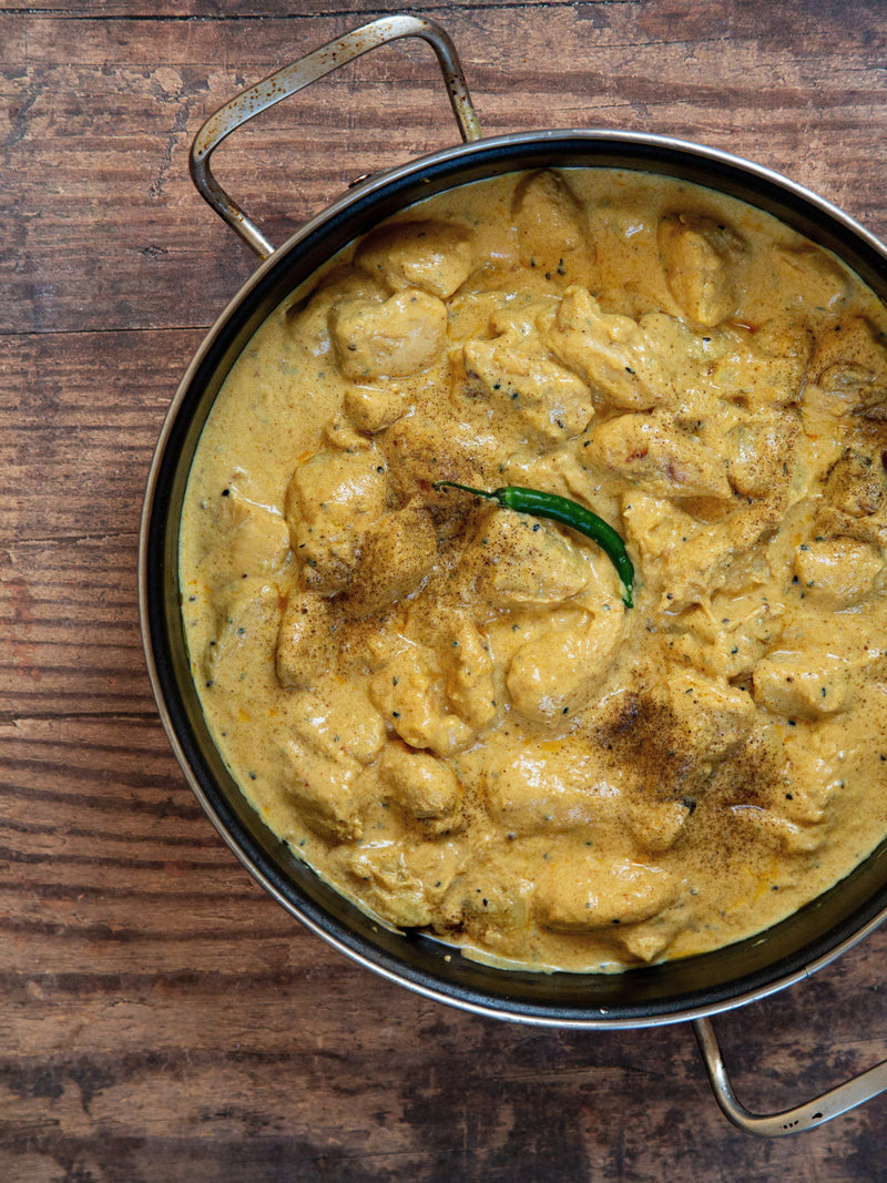 Mithi Ahmed mild and creamy Chicken Korma in a steel serving dish with a single green chilli on top