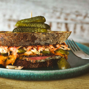 A Reuben-esque sandwich, made with coleslaw, pastrami and pickles