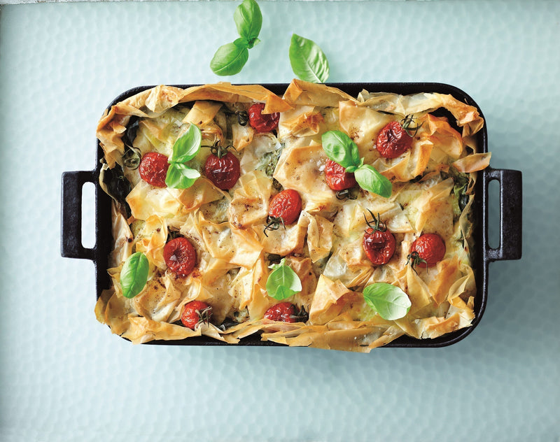 Garam Masala Bastilla topped with golden crispy filo pastry, cherry tomatoes and fresh basil leaves served in a rectangular baking dish