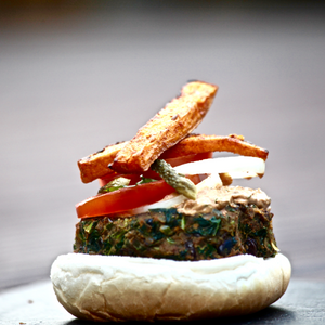 Vegetarian kale and masala burger, topped with sweet potato wedges and a healthy chipotle sauce