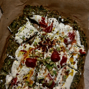 Courgette Flatbread with a light and creamy yoghurt topping, garnished with cherry tomatoes, chopped avocados and sesame seeds