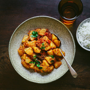 Hearty classic potato curry garnished with fresh coriander and served with a bowl of fluffy white rice