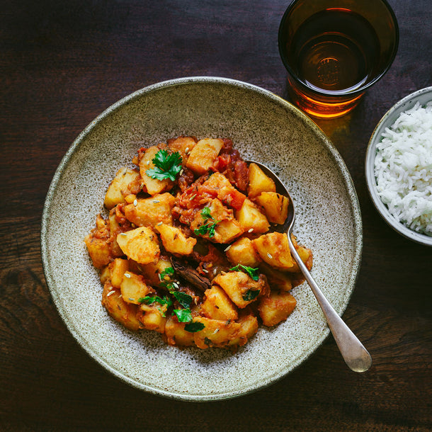 Hearty classic potato curry garnished with fresh coriander and served with a bowl of fluffy white rice