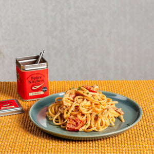 A perfectly cooked portion of Spice Kitchen’s Harissa & Boursin Linguine on a plate next to a Spice Kitchen Harissa tin.