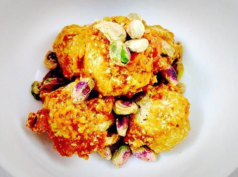 Golden pistachio dessert balls topped with crushed pistachios