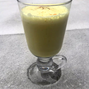 A tall glass of Neha D'Souza's warming turmeric latte garnished with strands of saffron