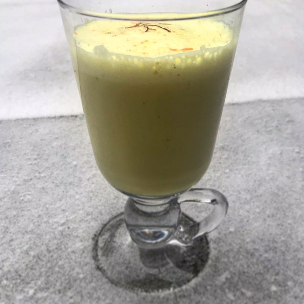 A tall glass of Neha D'Souza's warming turmeric latte garnished with strands of saffron