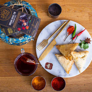 3 Vegetable Samosa on a plate next to a traditional Spice Kitchen round Spice tin