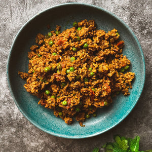A bowl of delicious lamb Keema with peas peppered around it 