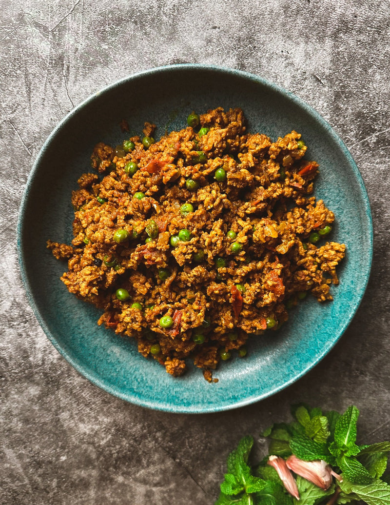 A bowl of delicious lamb Keema with peas peppered around it 
