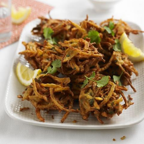 Crispy onion bhajis served with lemon wedges and fresh herbs