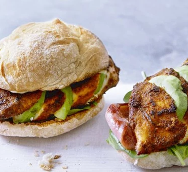 Fully loaded Cajun chicken burger with crispy spiced chicken, fresh salad, melted cheese, and creamy sauce in a soft bun.