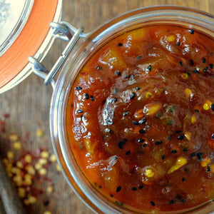 Jar of homemade spicy mango chutney with chili flakes and black sesame seeds