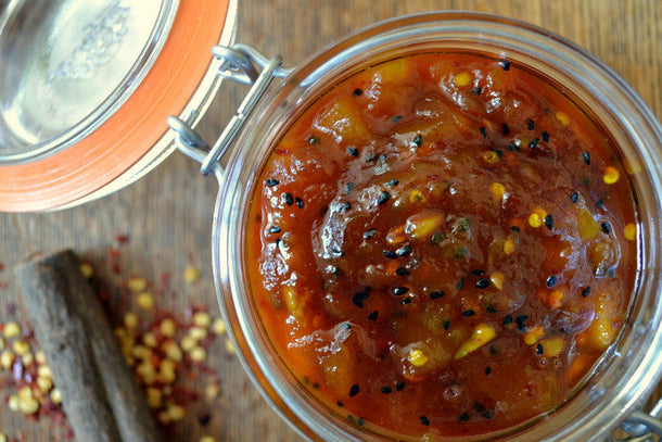 Jar of homemade spicy mango chutney with chili flakes and black sesame seeds