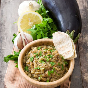 Smoky aubergine crush topped with herbs and olive oil, featuring charred roasted aubergine blended into a rich, creamy dip.
